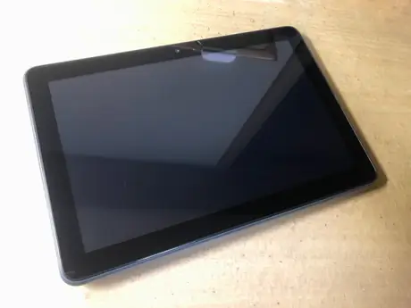 Dark blue Amazon Fire tablet angled on a light wood surface