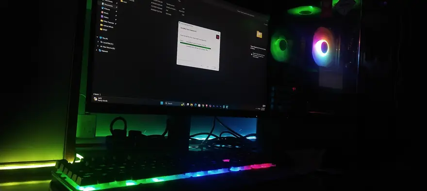 Budget gaming desktop setup with RGB lighting, keyboard, and monitor in a dim room