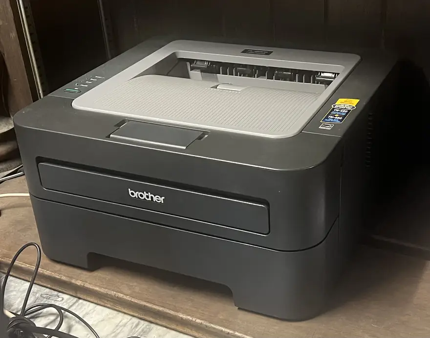 Compact Brother monochrome laser printer with output tray full of pages