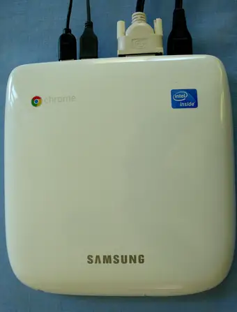 Small white Chromebox computer with HDMI cables plugged into the top edge