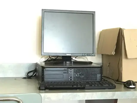 Budget desktop tower with an older monitor set up on a plain work desk