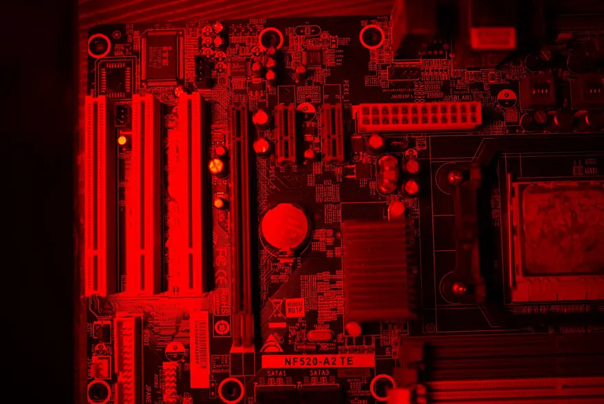 Macro photo of a red lit computer motherboard showing circuitry and components