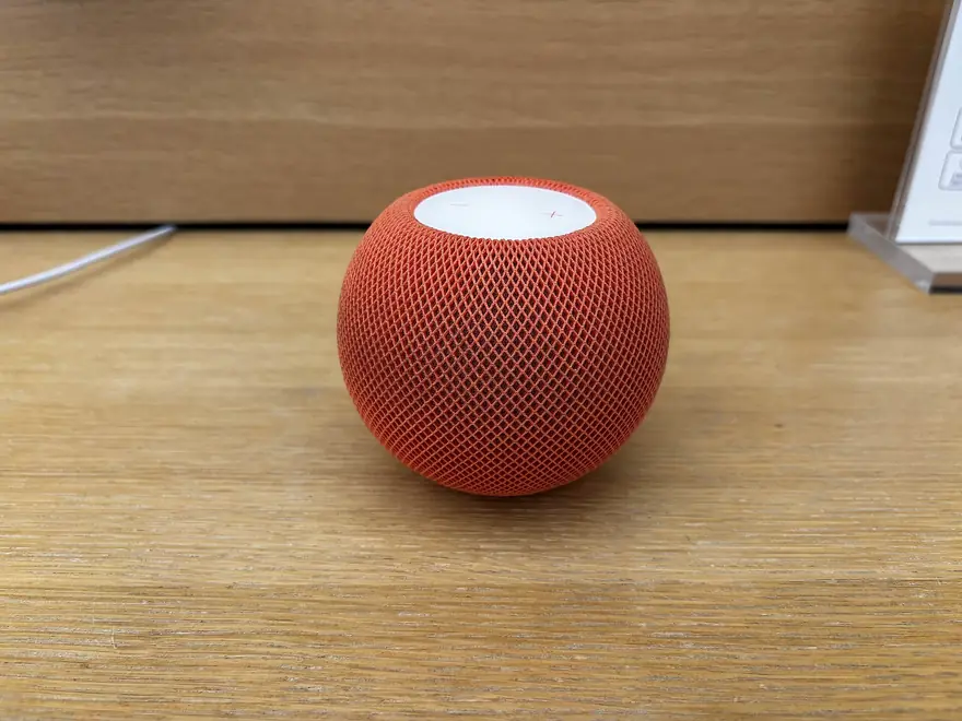 Apple HomePod mini smart speaker with glowing touch surface on a kitchen counter