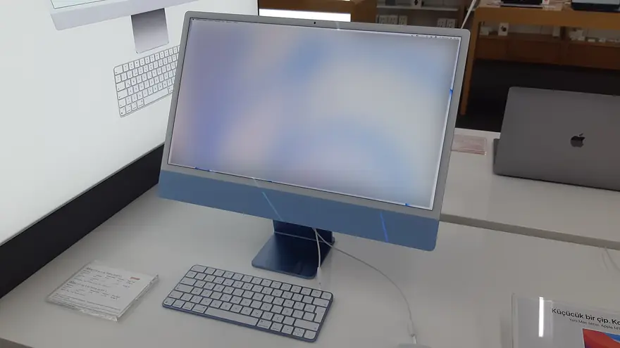 Blue 24 inch Apple iMac M4 with a matching Magic Keyboard on a bright display desk