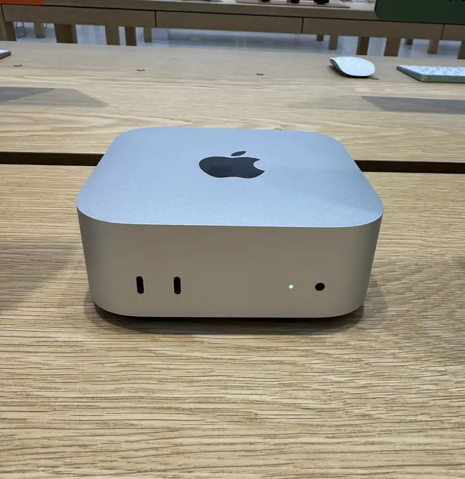 Silver Apple Mac mini M4 with front USB-C ports sitting on a light wood table