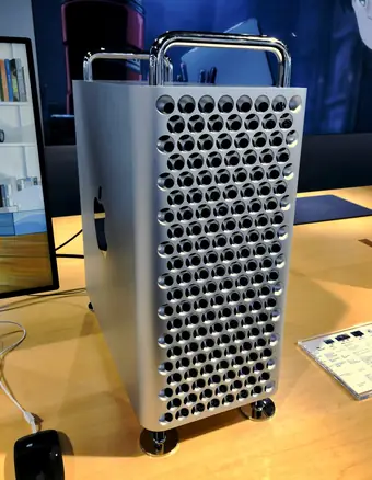 Apple Mac Pro tower with distinctive lattice grille beside a wooden desk