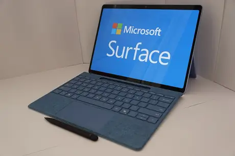 Microsoft Surface Pro with blue keyboard cover and stylus in front