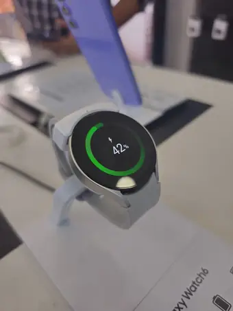 Silver Galaxy Watch charging on a store display stand with battery ring showing