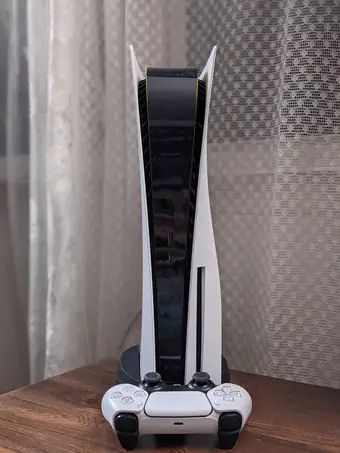 White PlayStation 5 console standing beside a DualSense controller