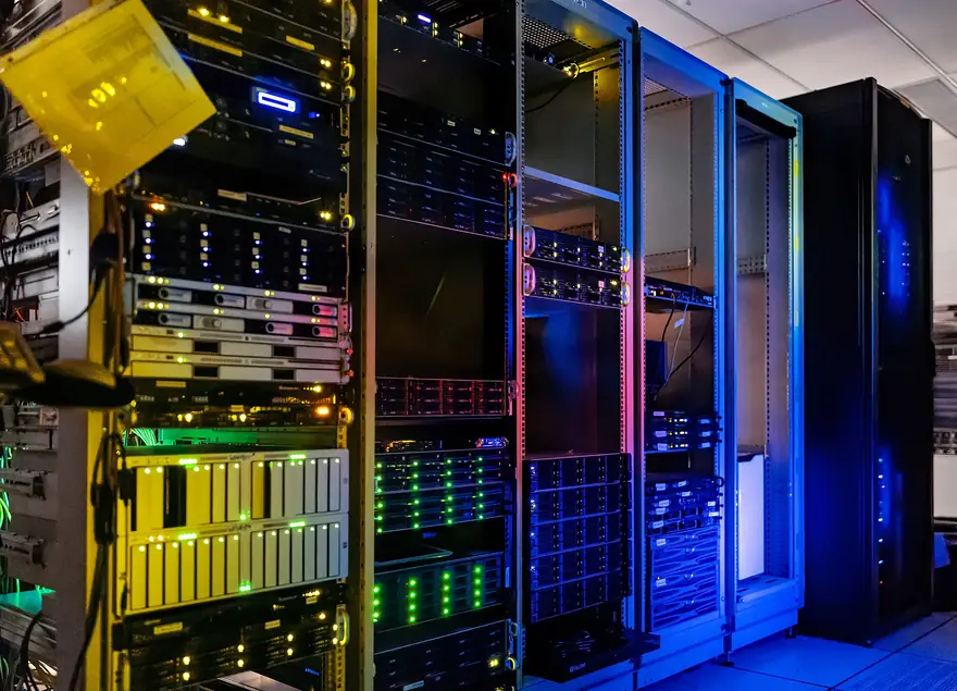 Rows of server racks glowing with green and blue lights inside a dark data center
