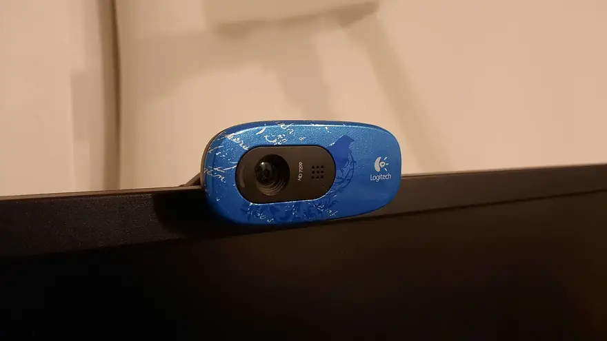 Blue patterned Logitech webcam clipped to the top edge of a dark computer monitor